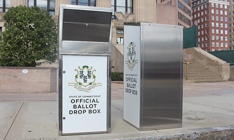 A silver ballot drop box next to another metal box.