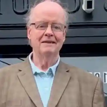 A man in glasses and a brown jacket