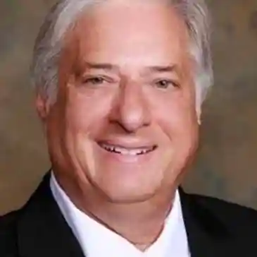 A man with white hair and wearing a suit.