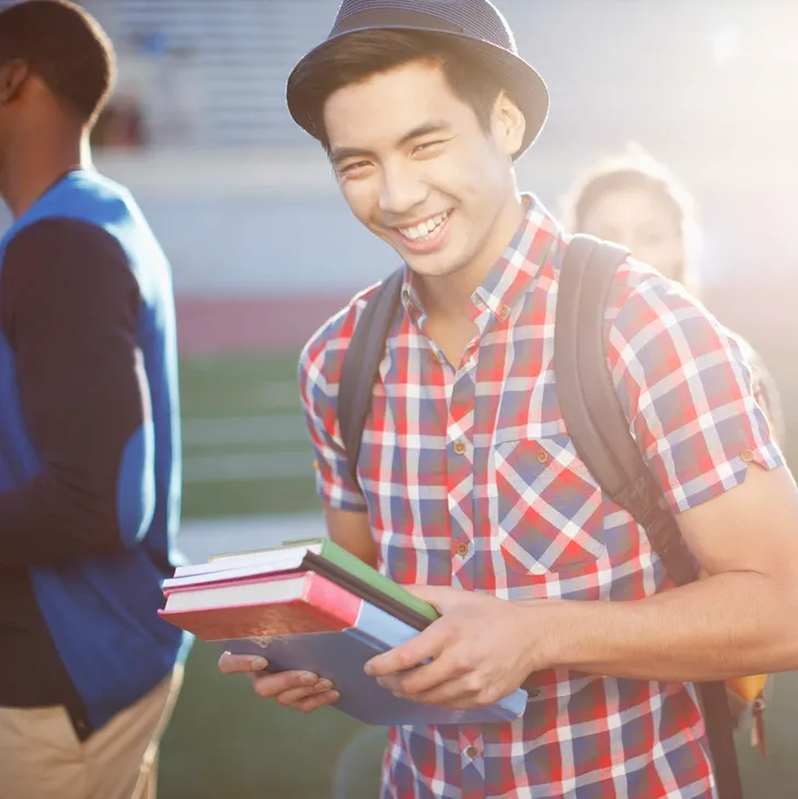 A man holding books in his hands while standing on the field.