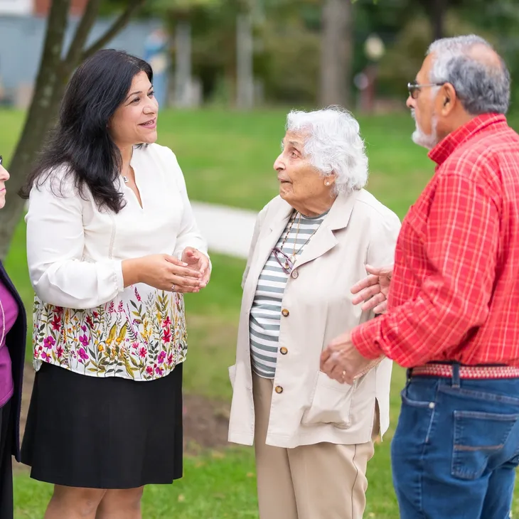 A group of people standing around talking to each other.