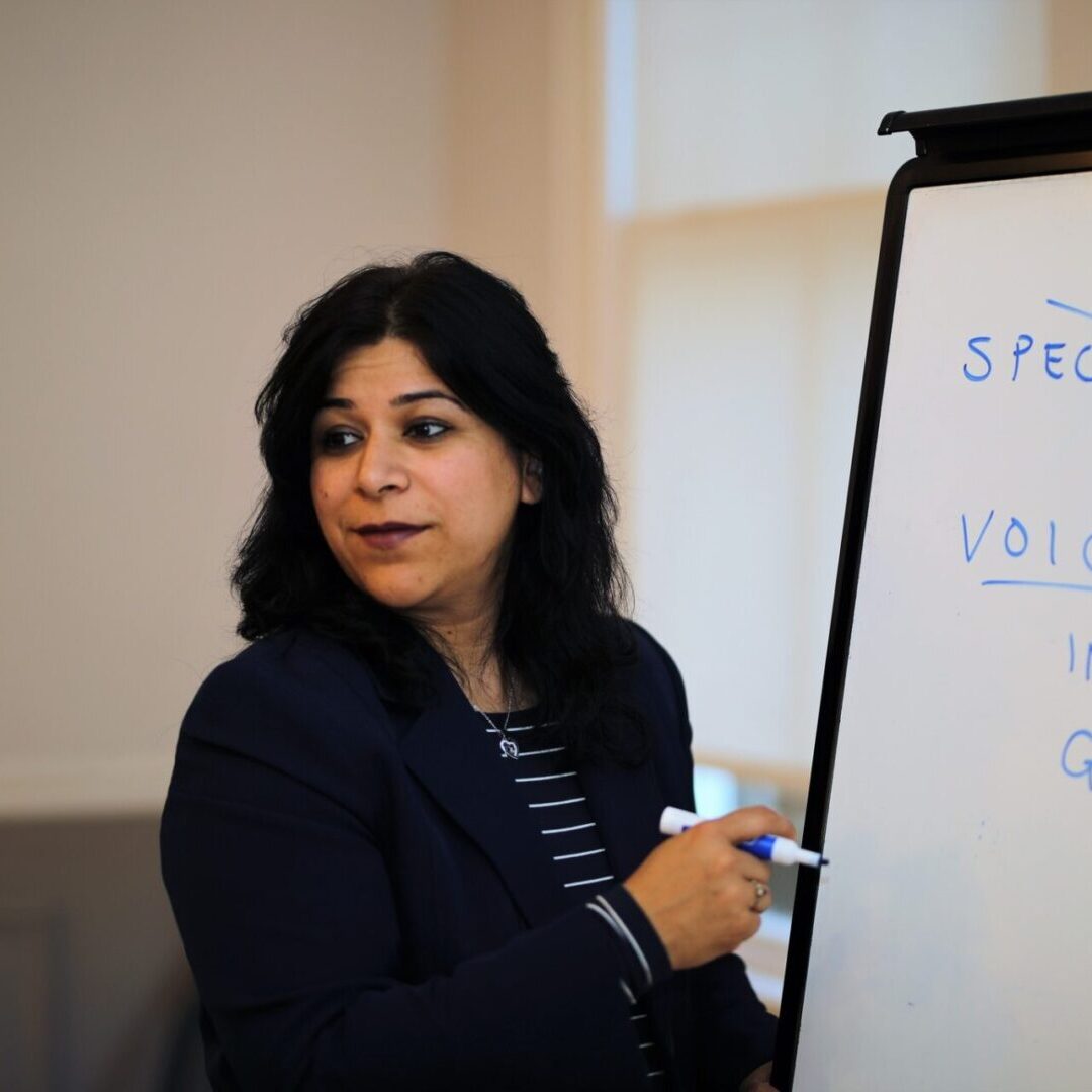 A woman is writing on a white board